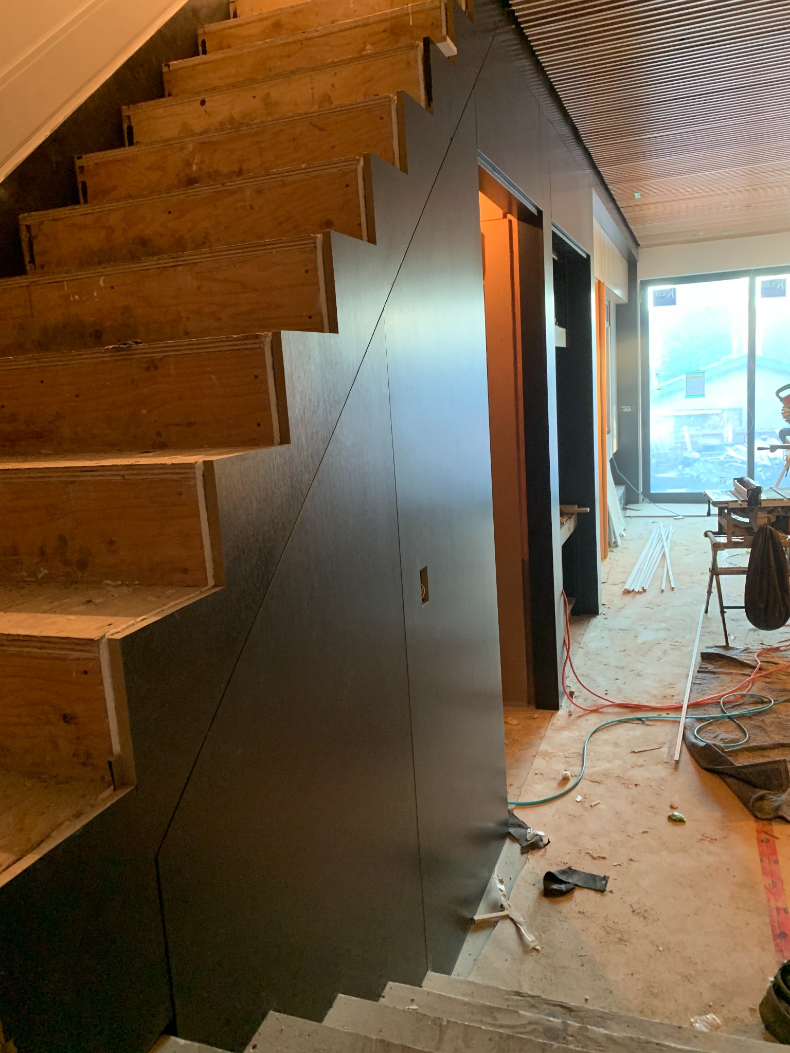Dark custom wall panels fitted precisely beside an open staircase